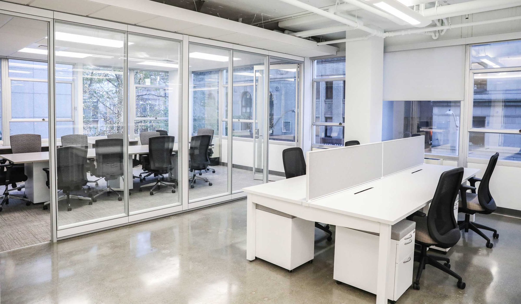 Open office workspace with glass-walled conference room and modern desking. Open office workspace with glass-walled conference room and modern desking.