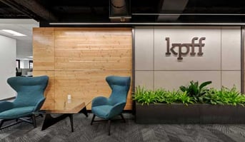 Office reception area with "kpff" signage, teal accent chairs, and decorative plants.