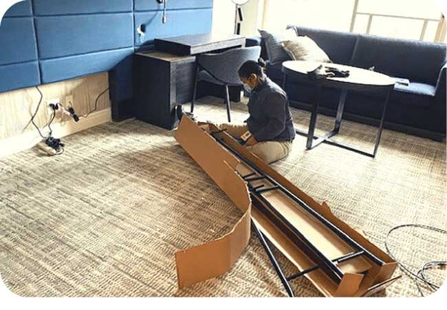 A person assembling a piece of furniture in an office environment.